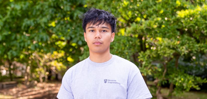 Portrait of Luis Delotavo standing in front of a green, leafy background